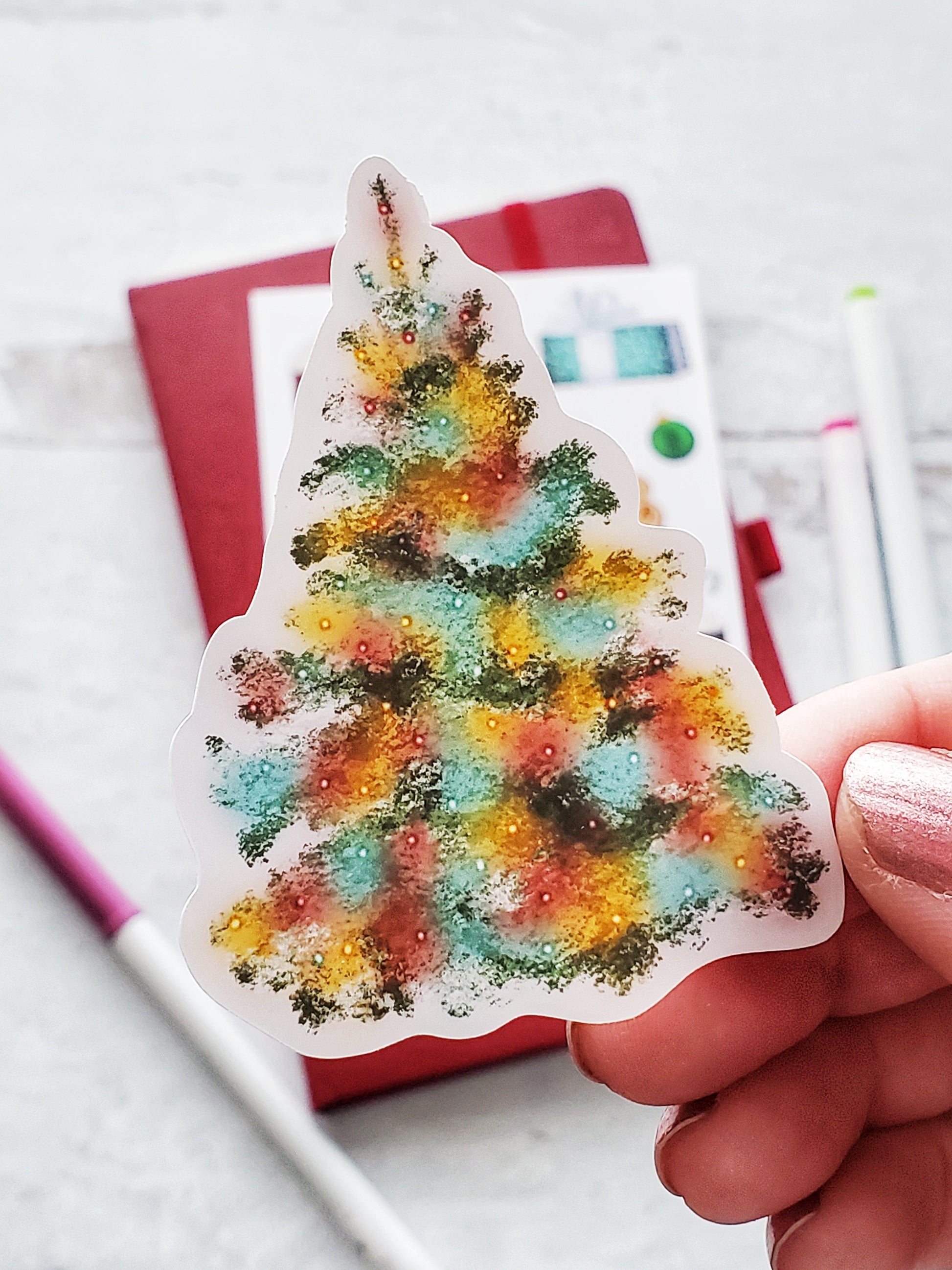 Close up of a Christmas tree sticker. The tree has colored lights that look like they are glowing. 