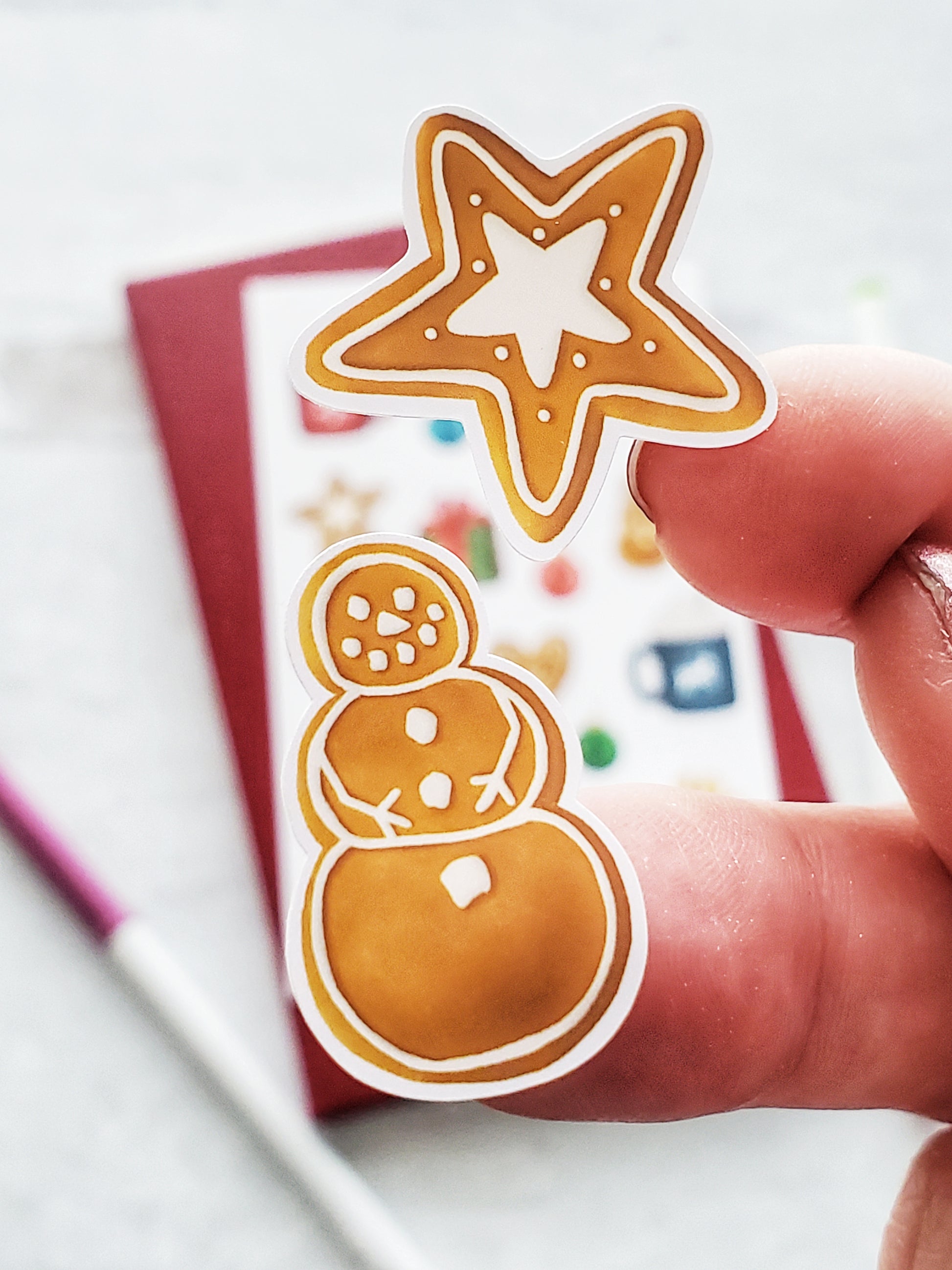 Close up of two gingerbread cookie stickers. One is a snowman the other is a star.