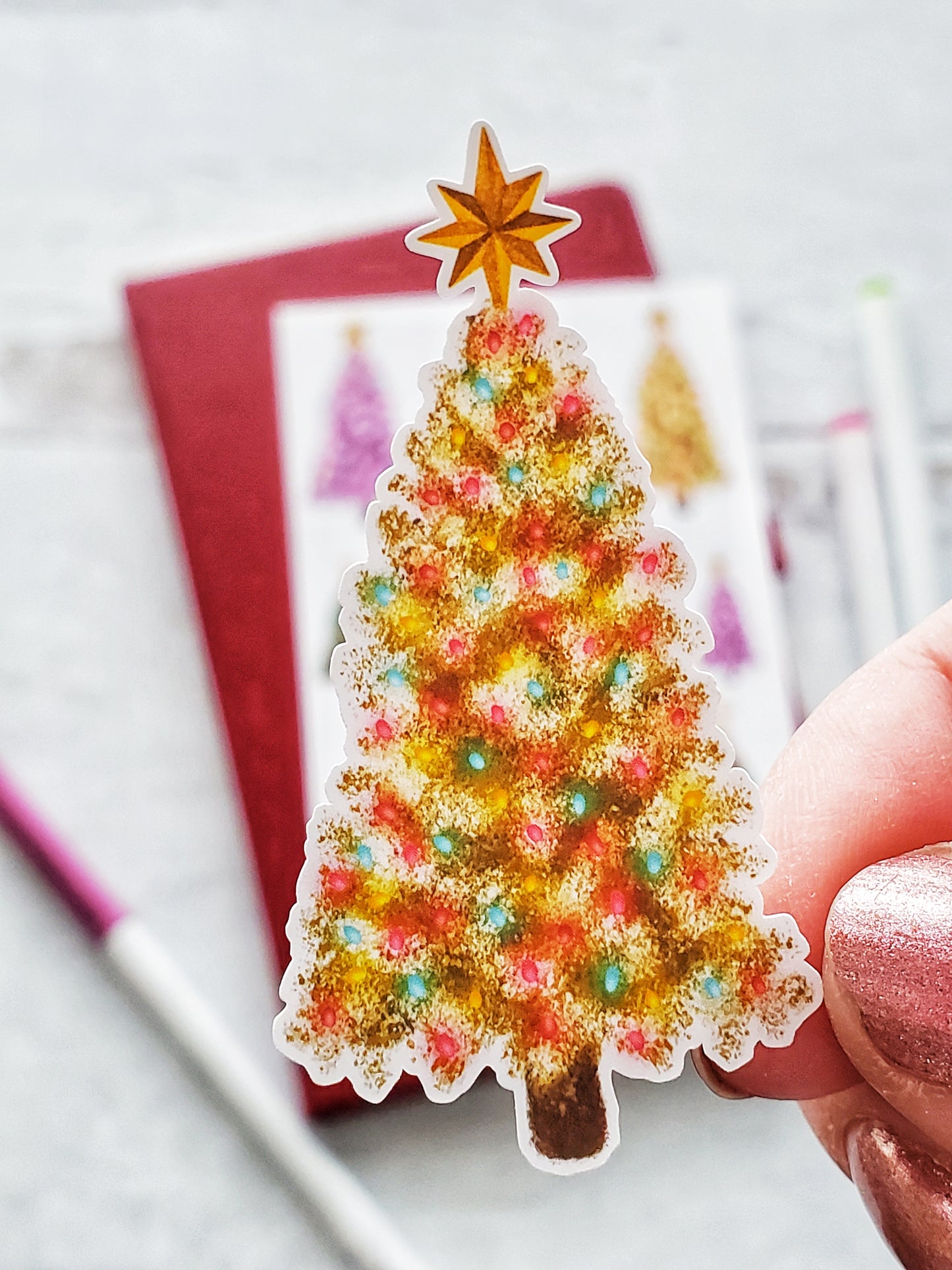 Close up of a sticker of a yellow Christmas tree with colorful lights and a gold topper. 