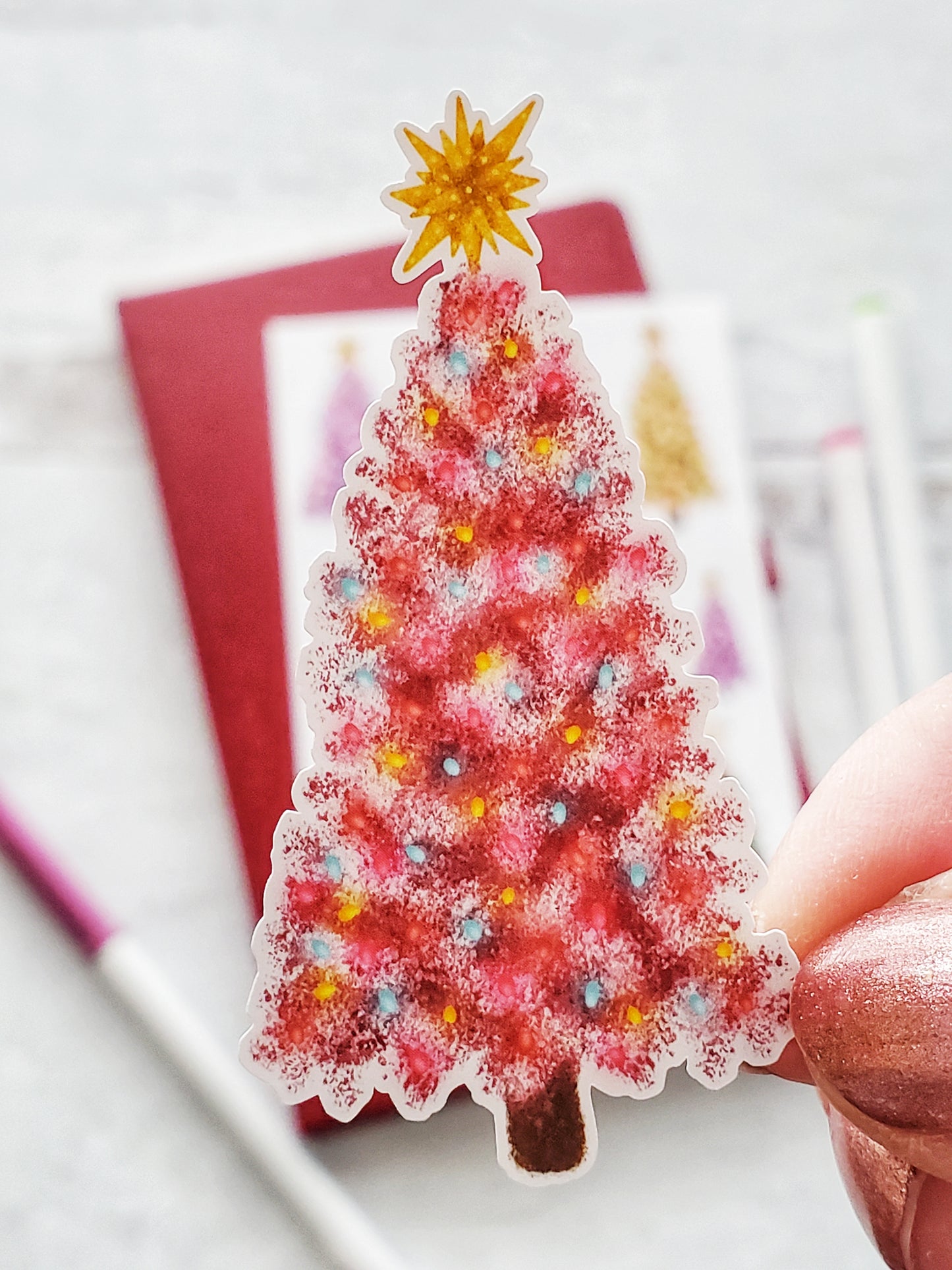 Close up of a pink Christmas tree sticker with colorful lights and a gold topper.