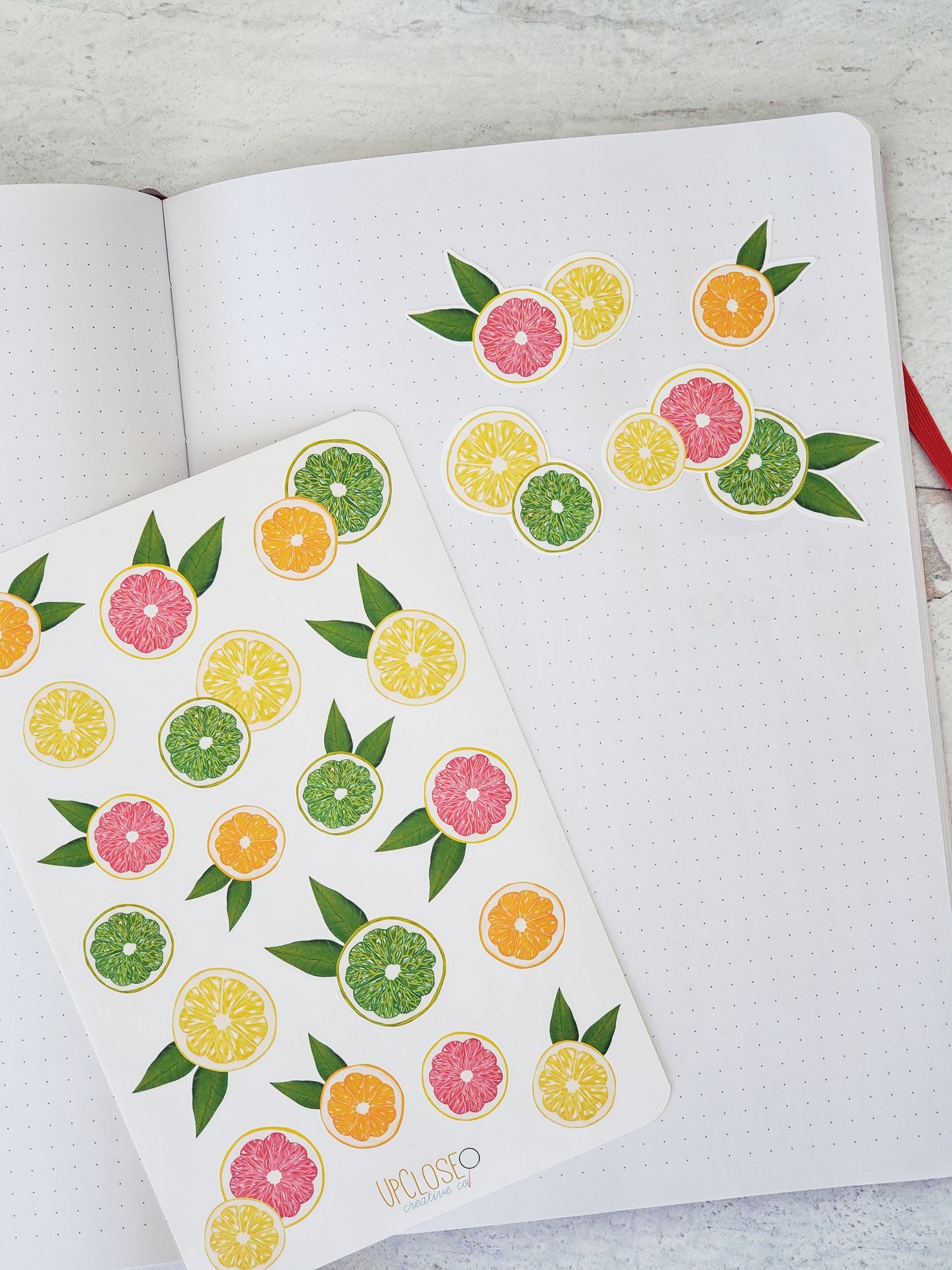 Stickers from the citrus fruits sticker sheet have been arranged on a dot grid journal page.