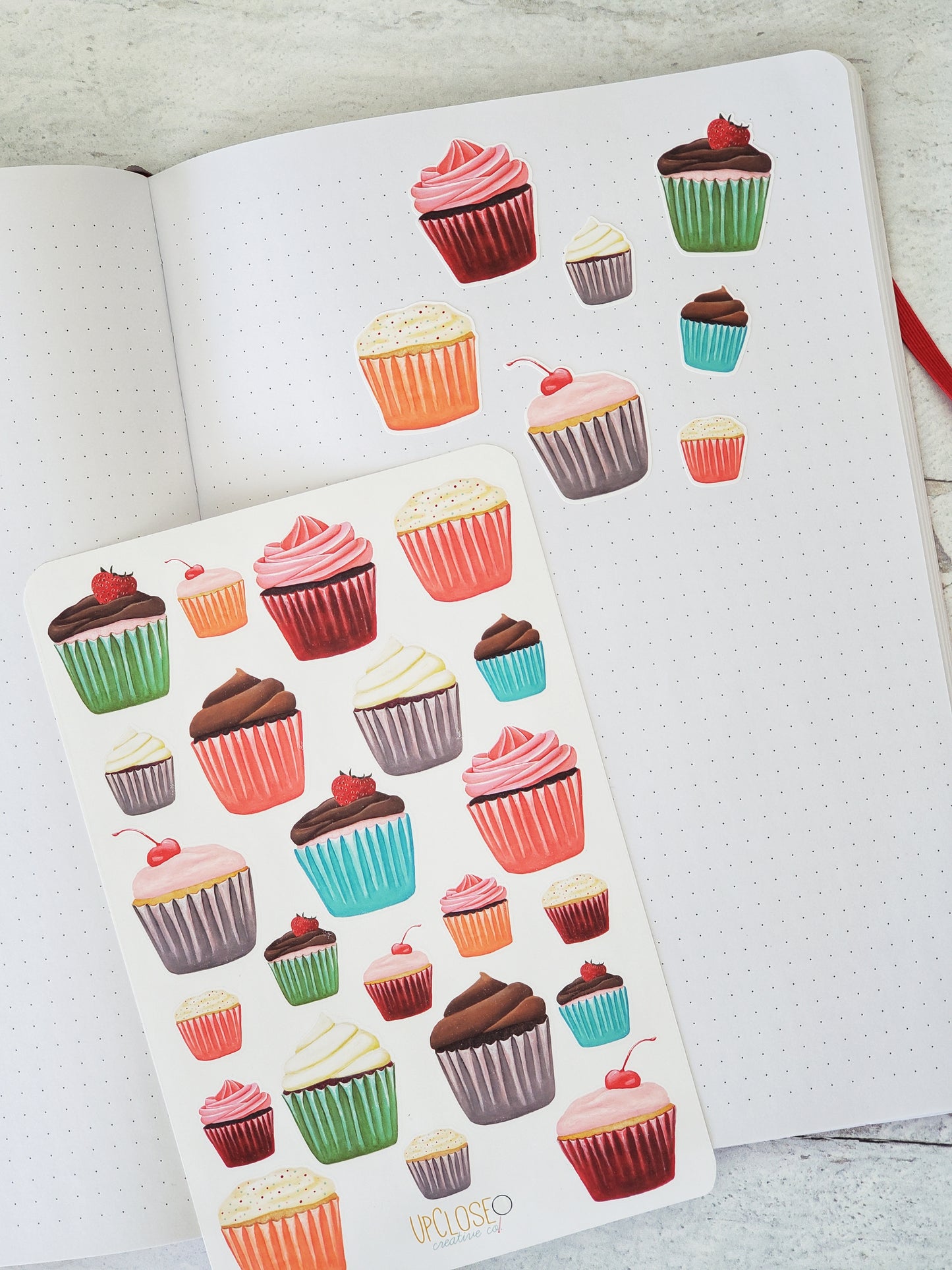 Several of the cupcake stickers have been arranged on a journal page. 