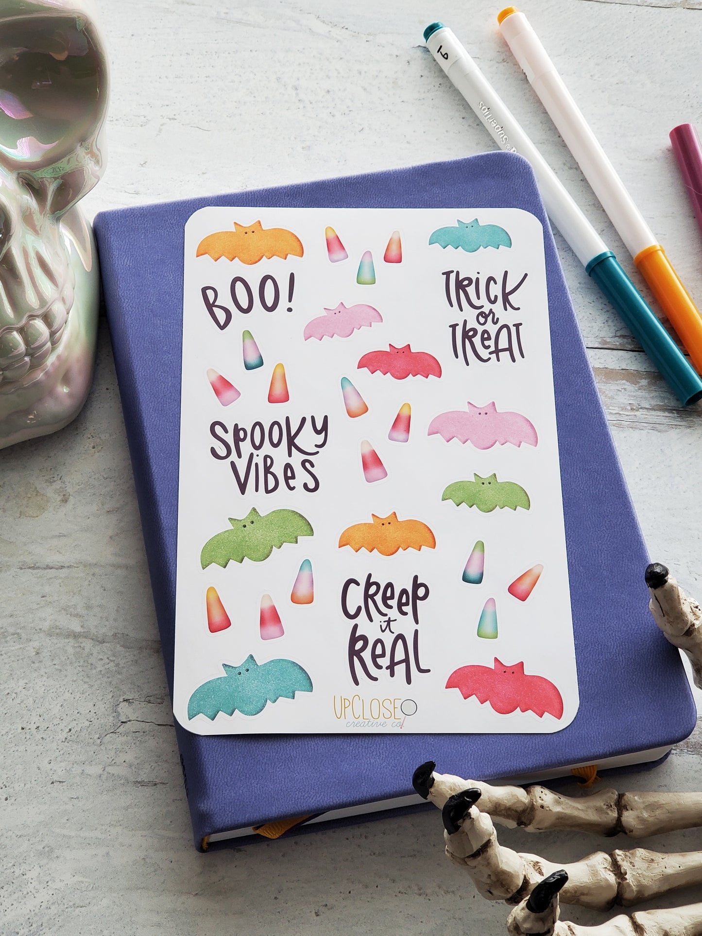 This sticker sheet has Halloween candies in bright colors and some popular Halloween phrases. There are gummy bats and candy corns in the colors pink, orange, green, blue and purple. The sayings are "boo!" "trick or treat" "Spooky vibes" and "creep it real".