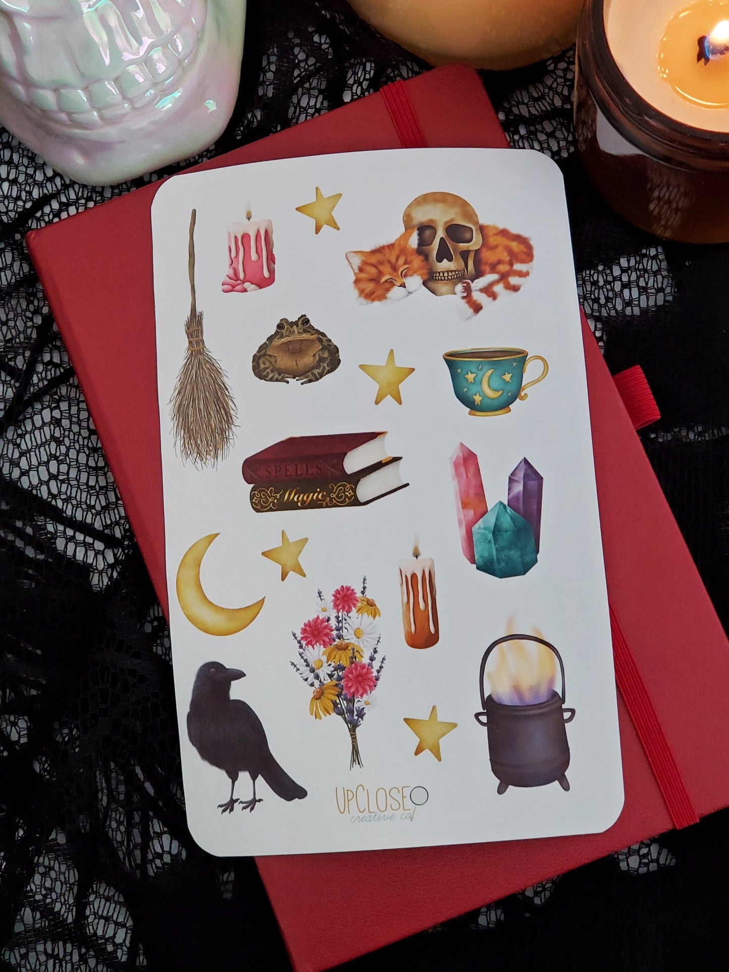 sticker sheet featuring witchy illustrations including a witch's broom, spell books, crystals, a cute cat cuddling with a skull and more. 