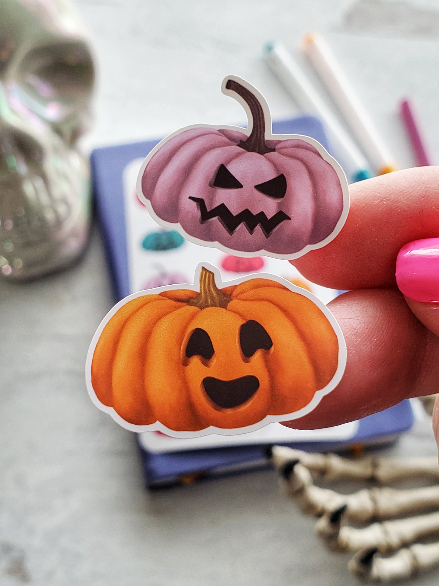 Close up of two jack-o-lantern stickers. One is purple with an angry face the other is orange with a laughing face.