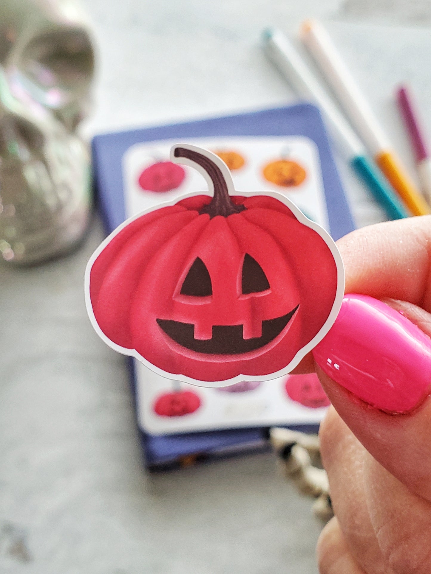 Close up of a pink, smiling jack-o-lantern sticker.